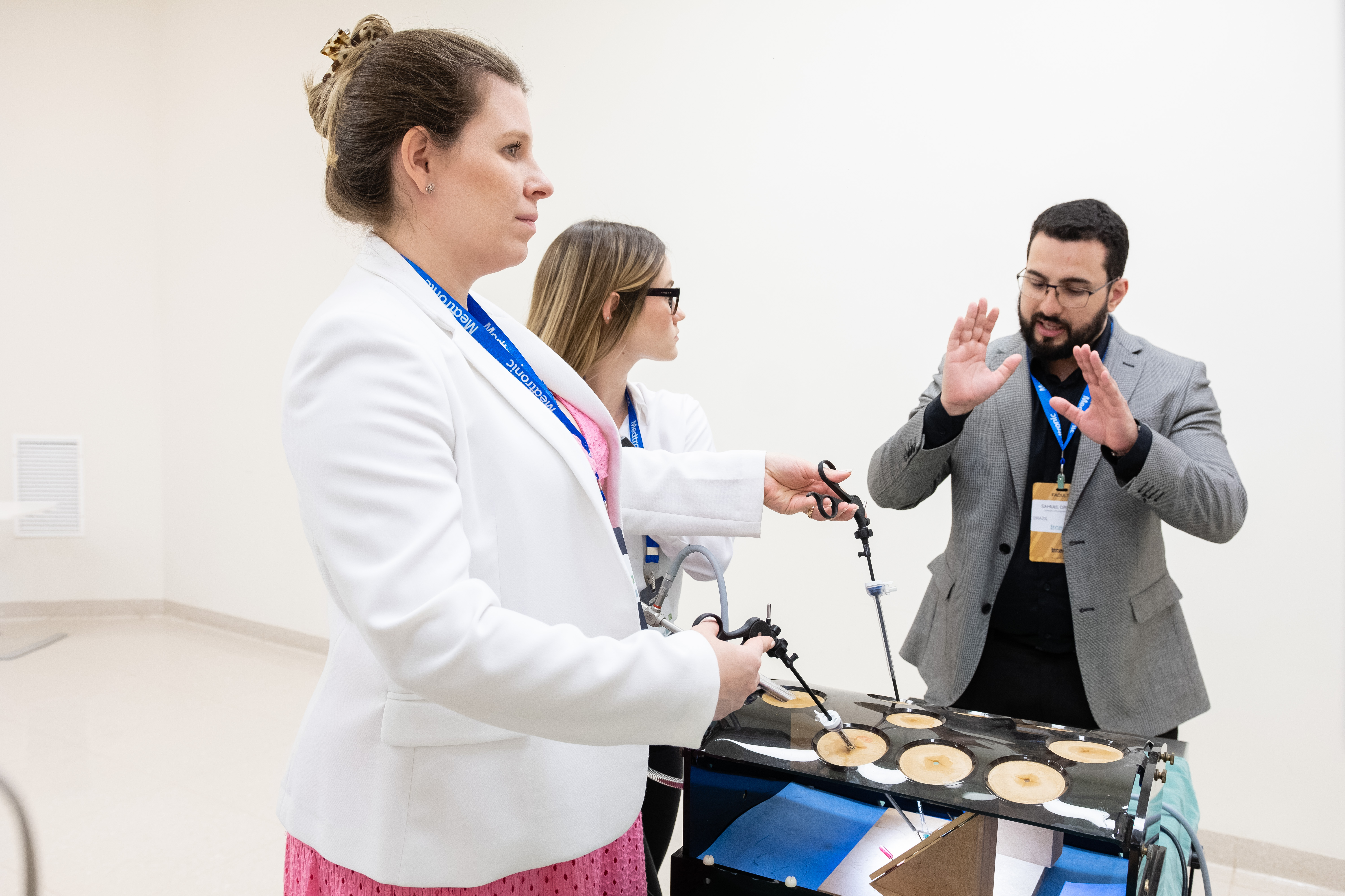 Dr. Samuel Drumond orientando duas médicas em treinamento com simulador cirúrgico