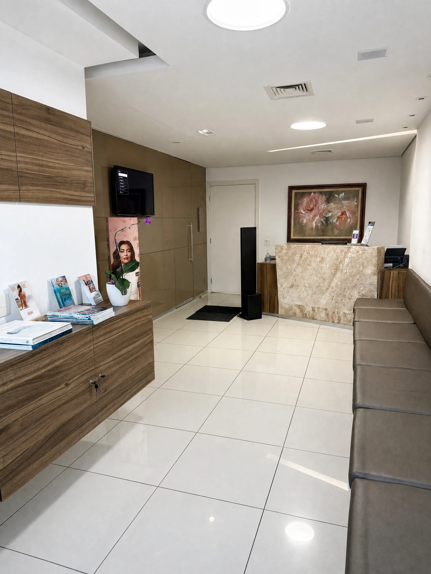 Sala de espera do consultório com balcão de recepção, mobiliário em madeira e quadro floral